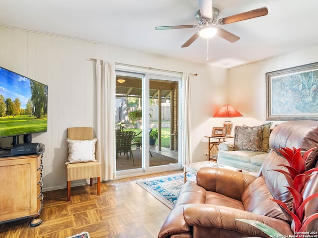 living room with ceiling fan, wood walls, and light parquet flooring