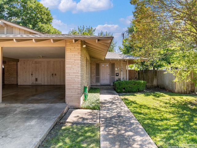 doorway to property with a yard and a carport