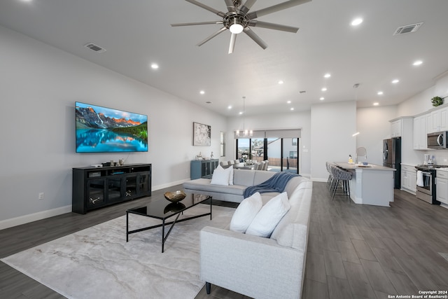 living room with ceiling fan with notable chandelier and dark hardwood / wood-style flooring