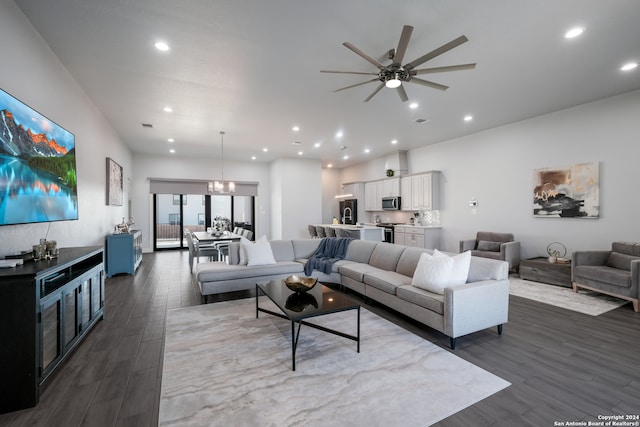 living room with ceiling fan with notable chandelier and dark hardwood / wood-style flooring