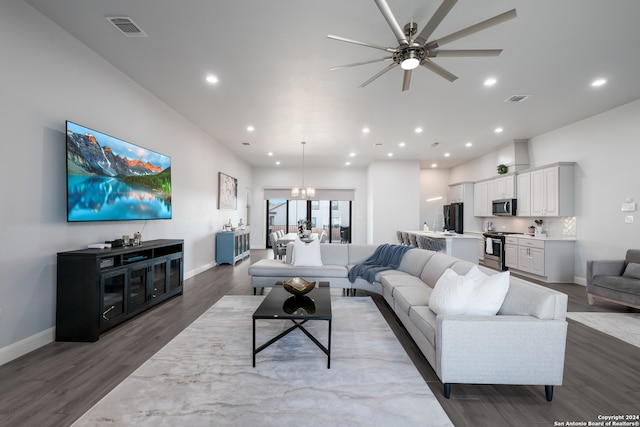 living room with ceiling fan with notable chandelier and dark wood-type flooring