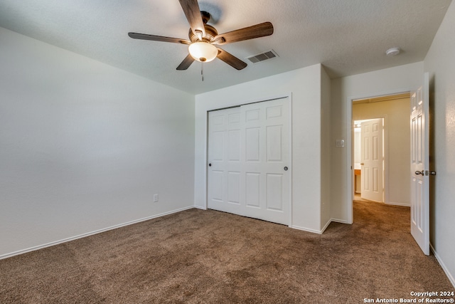 unfurnished bedroom featuring a textured ceiling, ceiling fan, dark carpet, and a closet