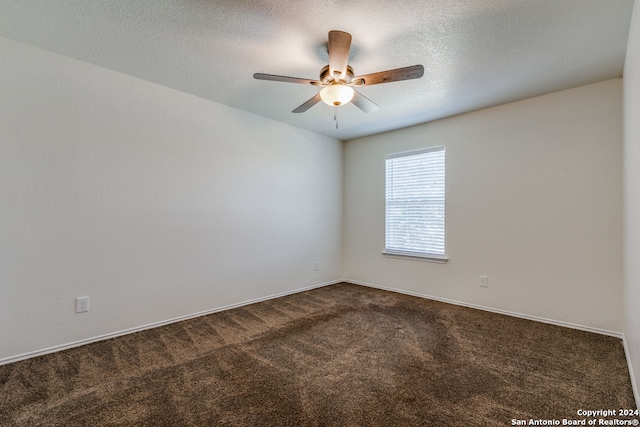 empty room featuring a textured ceiling, dark colored carpet, and ceiling fan