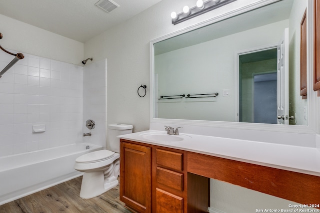 full bathroom featuring tiled shower / bath, vanity, toilet, a textured ceiling, and hardwood / wood-style floors