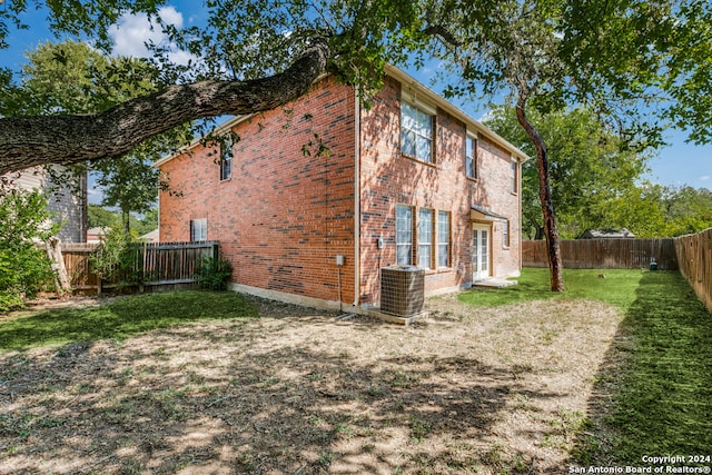 rear view of property featuring a lawn and central AC unit