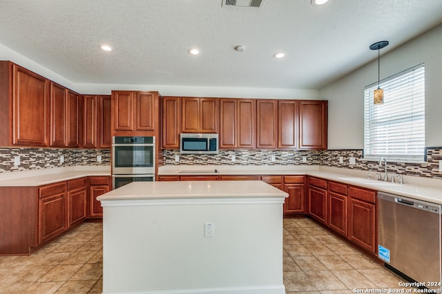 kitchen featuring pendant lighting, sink, a kitchen island, appliances with stainless steel finishes, and decorative backsplash