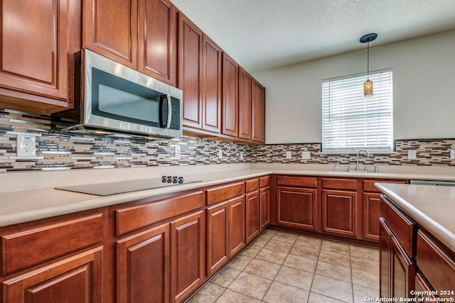 kitchen featuring black electric stovetop, a textured ceiling, hanging light fixtures, decorative backsplash, and light tile patterned floors