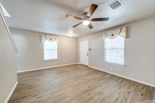 spare room with light hardwood / wood-style flooring, ceiling fan, and a textured ceiling