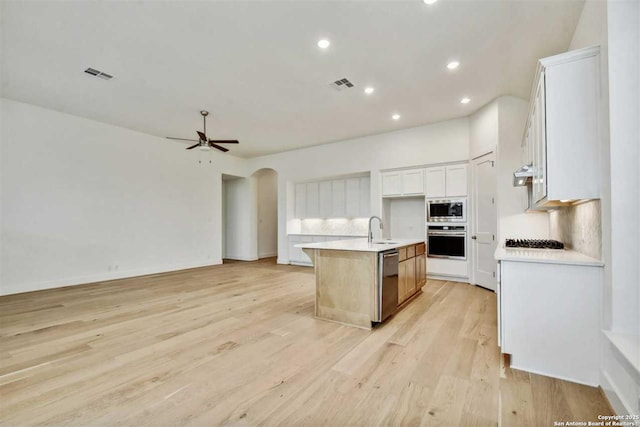 kitchen with sink, appliances with stainless steel finishes, an island with sink, decorative backsplash, and white cabinets