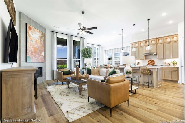 living room with ceiling fan, a healthy amount of sunlight, a fireplace, and light wood-type flooring