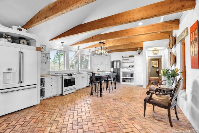 kitchen with pendant lighting, a notable chandelier, high end appliances, white cabinets, and a kitchen breakfast bar