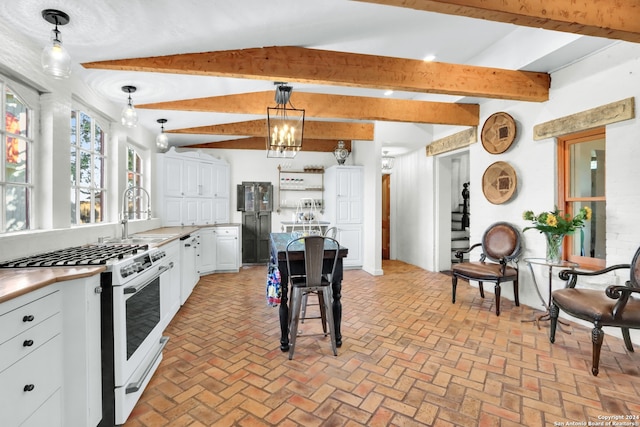 kitchen featuring pendant lighting, sink, white cabinetry, and high end range