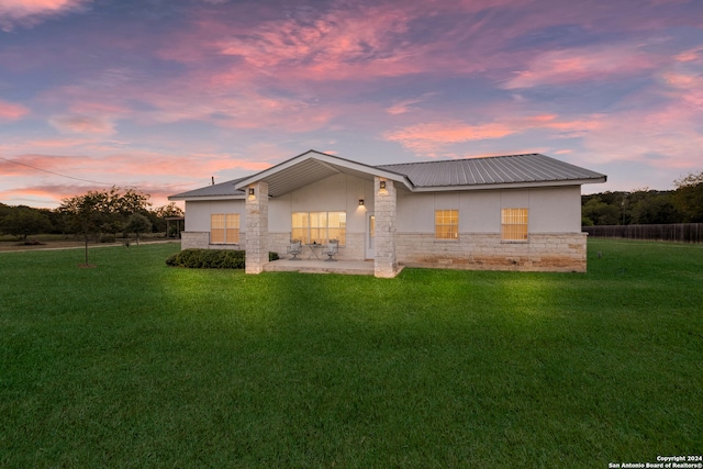 back house at dusk with a yard and a patio