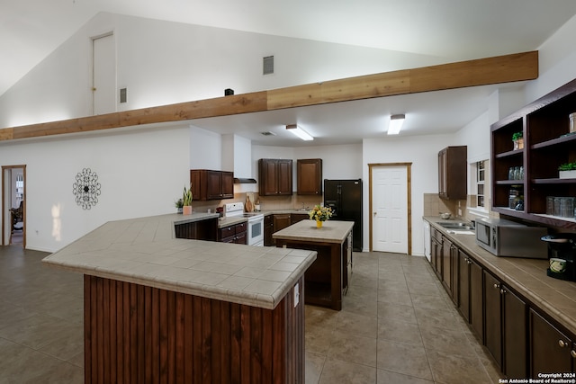 kitchen featuring black fridge, dark brown cabinets, tile counters, a center island, and white range with electric cooktop