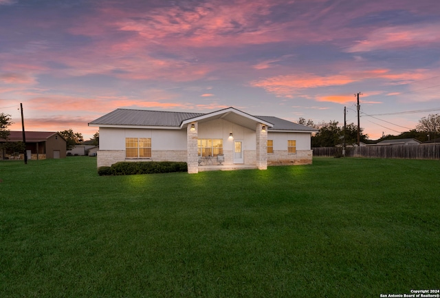 back house at dusk featuring a yard