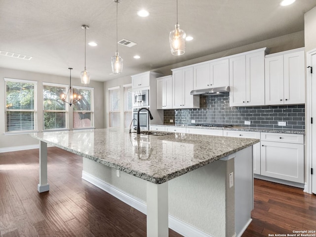 kitchen with decorative light fixtures, a large island with sink, and white cabinets