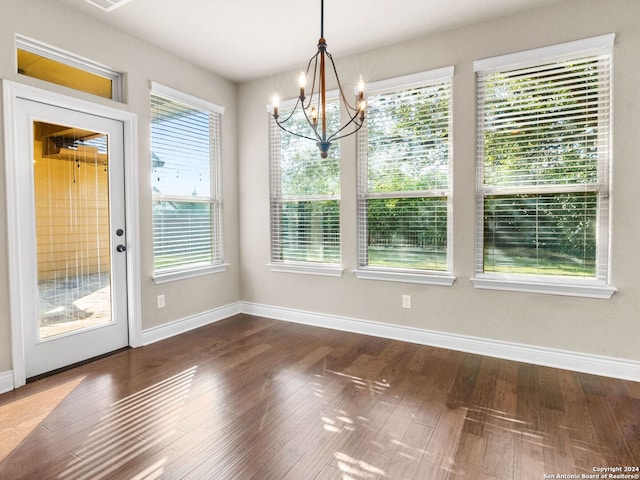 unfurnished dining area with a notable chandelier and dark wood-type flooring