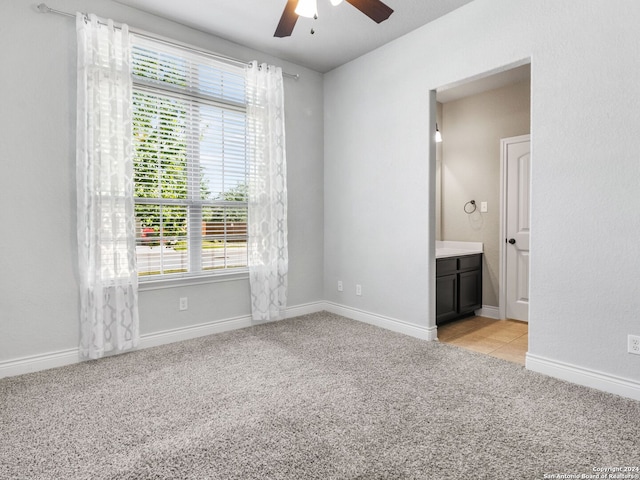 unfurnished bedroom featuring light carpet, connected bathroom, and multiple windows