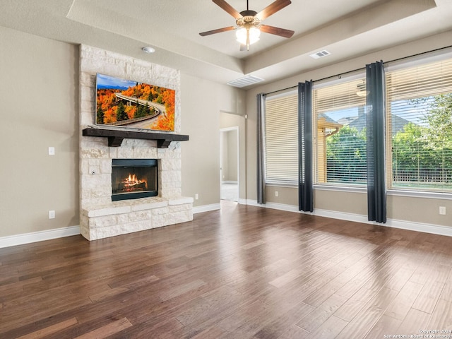 unfurnished living room featuring ceiling fan, a raised ceiling, wood-type flooring, a textured ceiling, and a fireplace