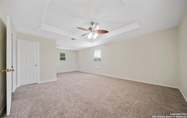 empty room with ceiling fan, a tray ceiling, and carpet flooring