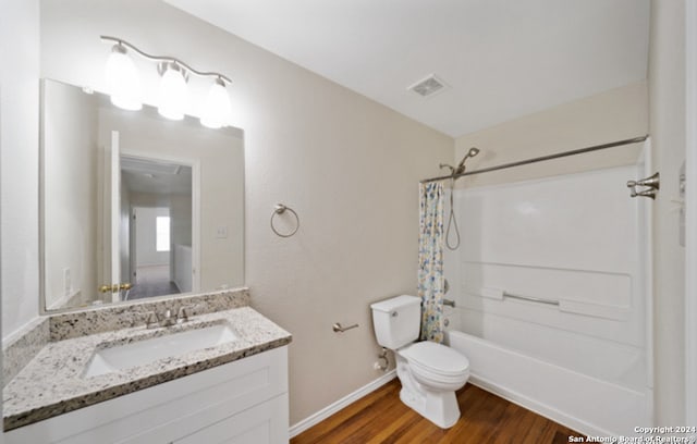 full bathroom with wood-type flooring, vanity, shower / bath combo with shower curtain, and toilet