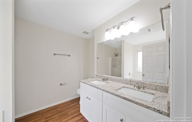 bathroom with walk in shower, vanity, hardwood / wood-style floors, and toilet