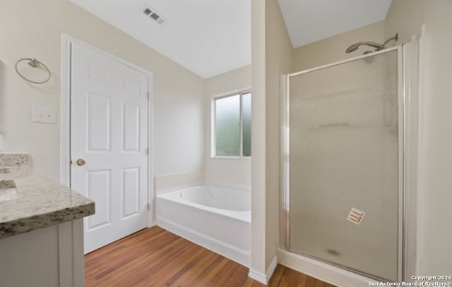 bathroom featuring vanity, lofted ceiling, independent shower and bath, and hardwood / wood-style floors