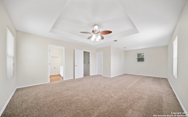 unfurnished bedroom featuring a tray ceiling, light carpet, and ceiling fan