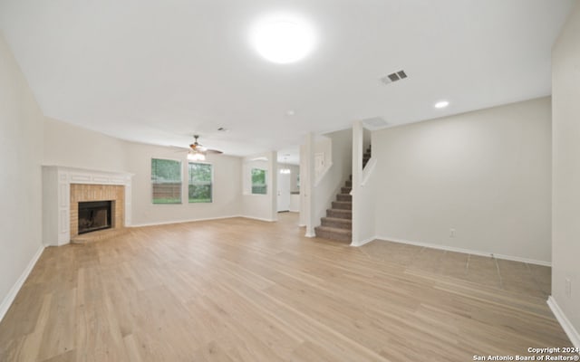 unfurnished living room featuring a brick fireplace, light wood-type flooring, and ceiling fan