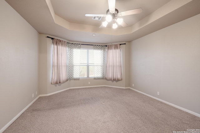 carpeted empty room with a tray ceiling and ceiling fan