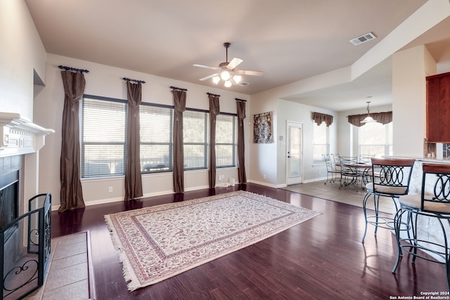 living room with ceiling fan, a tile fireplace, and dark hardwood / wood-style flooring