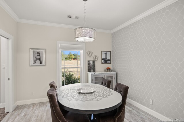 dining area featuring light wood-type flooring and crown molding