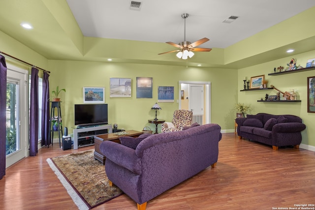 living room featuring a tray ceiling, ceiling fan, and hardwood / wood-style floors