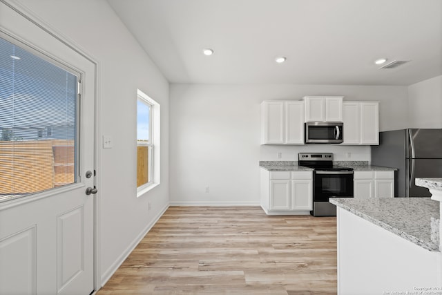 kitchen with light hardwood / wood-style flooring, stainless steel appliances, white cabinetry, and light stone counters