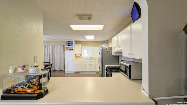 kitchen with a textured ceiling, sink, kitchen peninsula, and white cabinetry