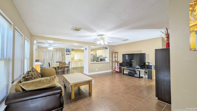 tiled living room with a textured ceiling and ceiling fan