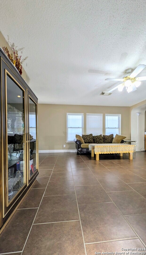 unfurnished living room with dark tile patterned floors, a textured ceiling, and a healthy amount of sunlight