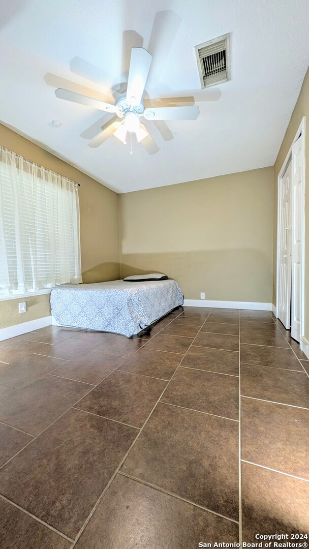 unfurnished bedroom with dark tile patterned floors and ceiling fan