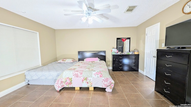 tiled bedroom with ceiling fan and a textured ceiling