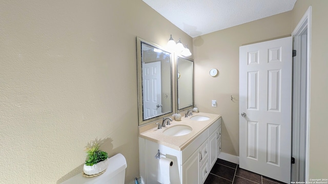 bathroom with tile patterned flooring, a textured ceiling, vanity, and toilet