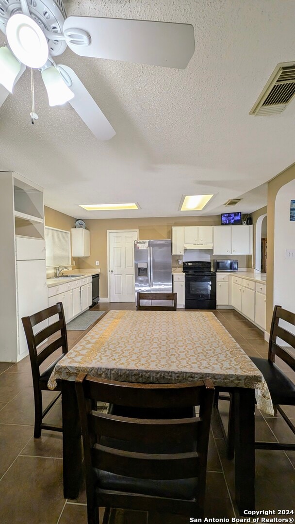 dining room featuring dark tile patterned floors, a textured ceiling, ceiling fan, and sink