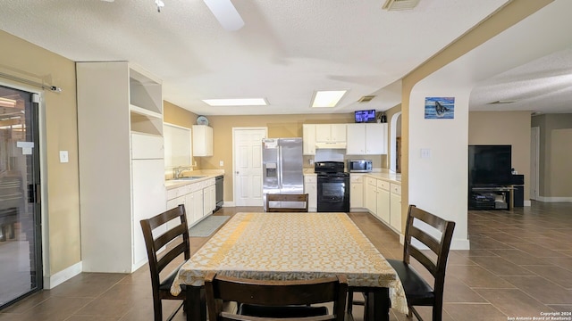 kitchen featuring a textured ceiling, sink, dark tile patterned floors, and black appliances