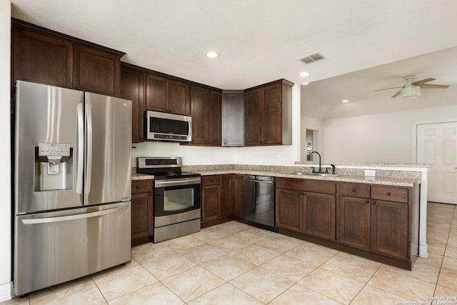 kitchen with light stone countertops, ceiling fan, sink, appliances with stainless steel finishes, and dark brown cabinets