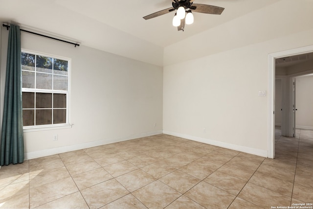 tiled empty room featuring vaulted ceiling and ceiling fan