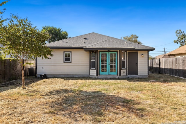 rear view of house with french doors and a lawn