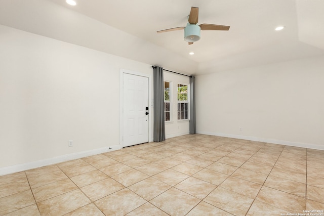 empty room with ceiling fan, vaulted ceiling, and light tile patterned floors