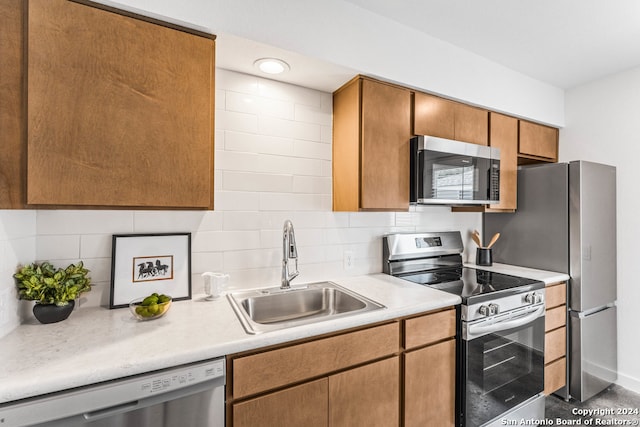 kitchen with appliances with stainless steel finishes, sink, and tasteful backsplash