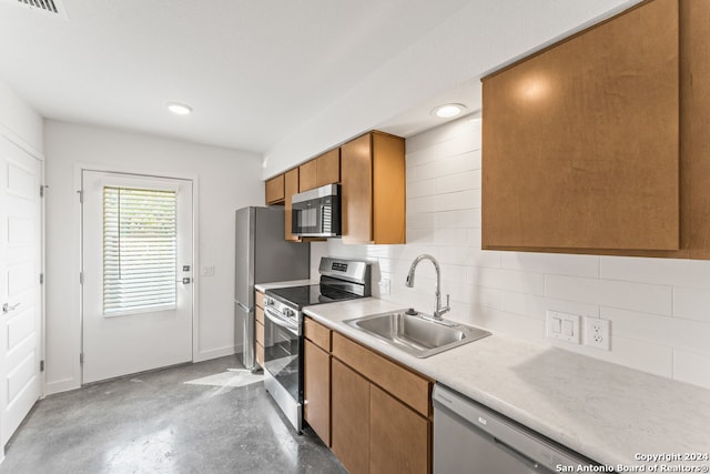 kitchen featuring appliances with stainless steel finishes, backsplash, sink, and concrete floors