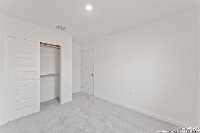 unfurnished bedroom with a closet and light colored carpet