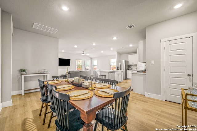 dining space with ceiling fan, a textured ceiling, and light hardwood / wood-style floors